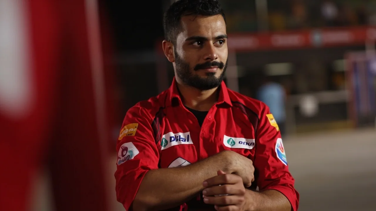 Close-up of a pace bowler in mid-delivery stride, front leg braced and arm coming over, with the batter's stance in soft focus behind him